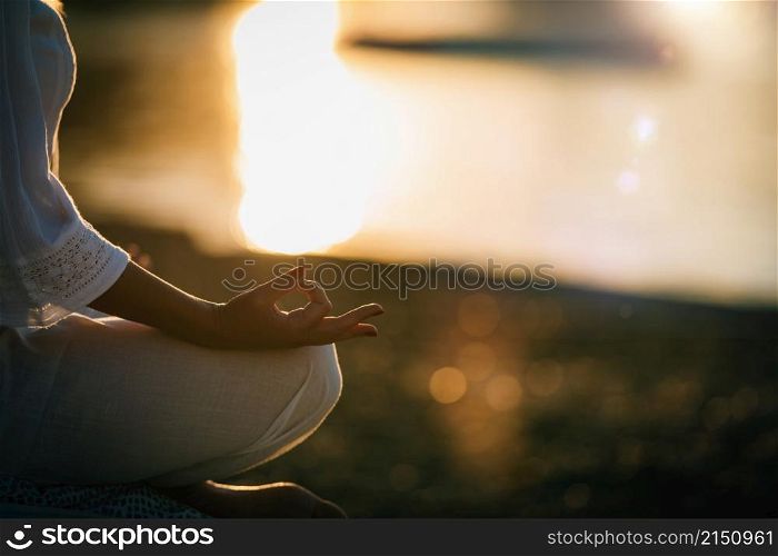 Sungazing. Woman meditating by the lake, sitting in lotus position. . Sungazing. Woman Sun Gazing and Meditating by the Lake in Lotus Position.