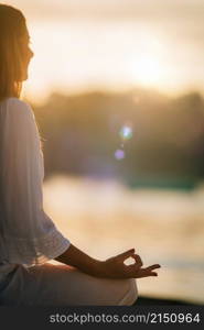 Sungazing. Woman meditating by the lake, sitting in lotus position. . Sungazing. Woman Sun Gazing and Meditating by the Lake in Lotus Position.