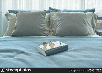 Sunglasses and book setting on bed in blue color scheme