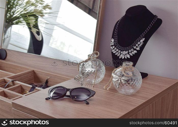 Sunglasses crystal jars and necklace on dressing table