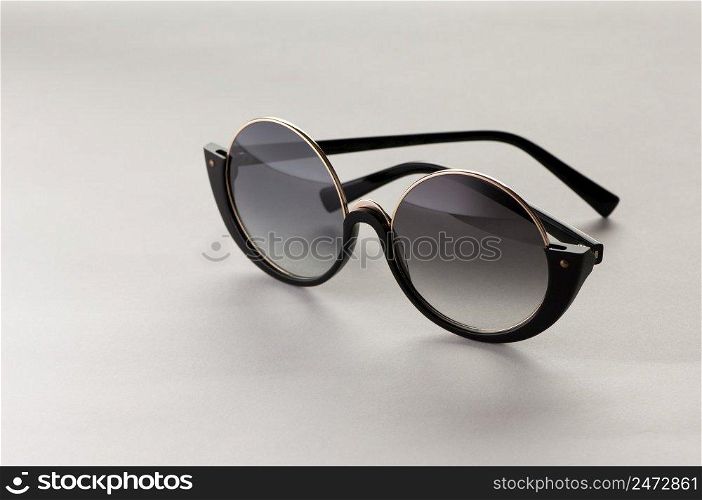 Sunglasses in a circular frame on a light background with reflection. Sunglasses on a white background light