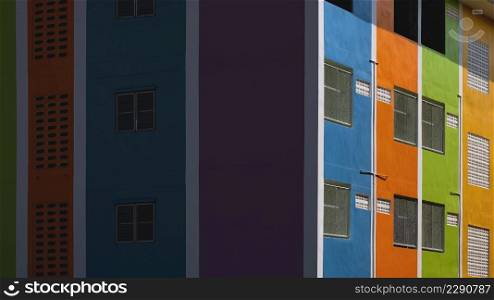 Sunlight and shadow on surface of colorful apartment building wall at morning time in perspective side view