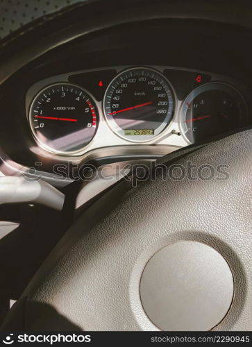 Sunlight and shadow on surface of steering wheel with car dashboard panel and indicator lights inside of pickup car in vertical frame