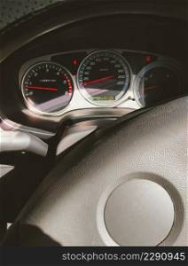Sunlight and shadow on surface of steering wheel with car dashboard panel and indicator lights inside of pickup car in vertical frame
