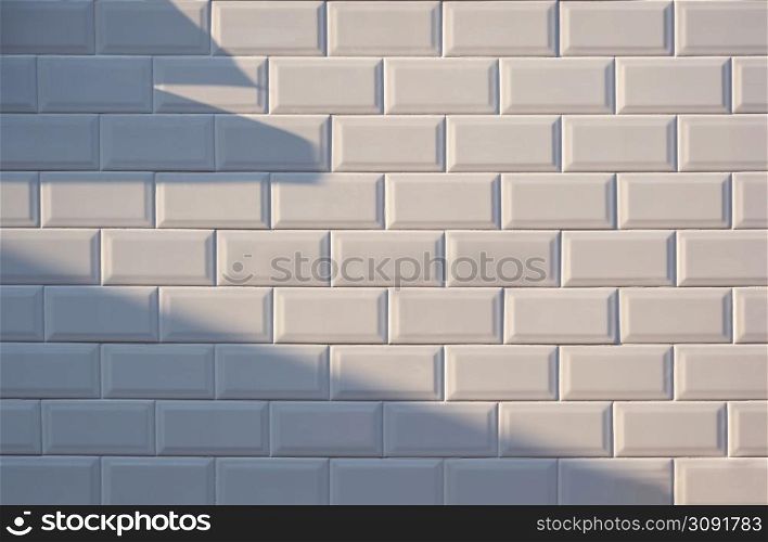 Sunlight and shadow on surface of white tile wall background