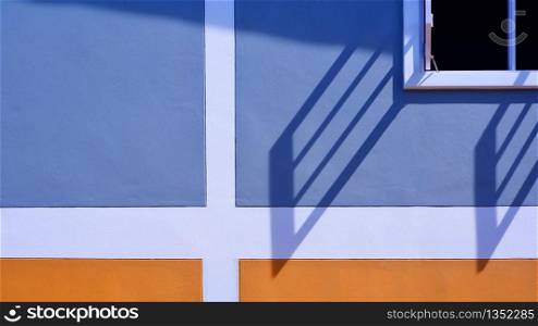 Sunlight and shadow on surface of white wooden window with blue and orange painted wall decoration background, exterior architecture concept