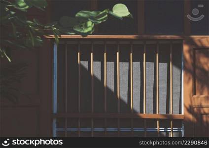 Sunlight and shadow on wooden window surface of the old vintage house with blurred green branch on foreground
