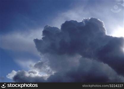Sunlight Filtering Through Large Dark Clouds In Blue Sky