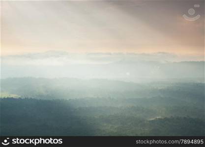 Sunlight shines through the clouds into the mountains and forests. Mist-covered mountains and trees.
