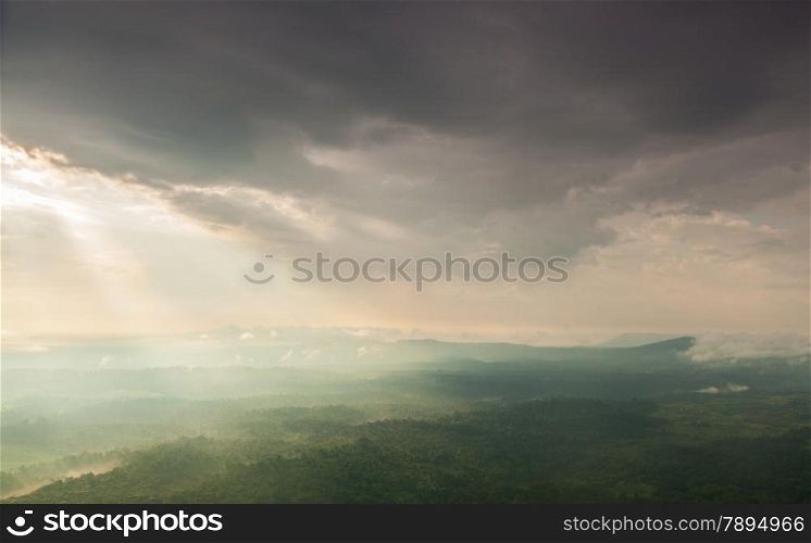Sunlight shines through the clouds into the mountains and forests. Mist-covered mountains and trees.
