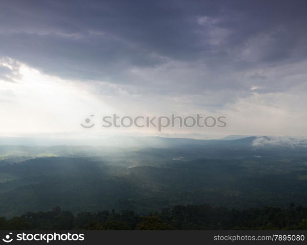 Sunlight shines through the clouds into the mountains and forests. Mist-covered mountains and trees.