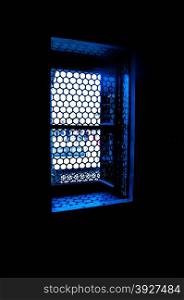 Sunlight shining through a lattice window in a dark room.