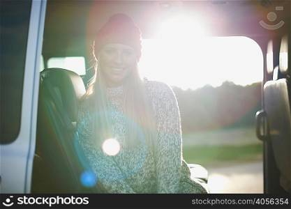 Sunlit portrait of young woman sitting in back of car