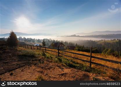 Sunny and foggy morning in Carpathian mountains. Village on the misty hills.