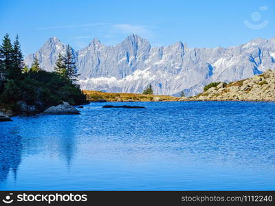 Sunny autumn alpine view. Peaceful mountain forest lake with clear transparent water and reflections. Spiegelsee or Mirror Lake, Reiteralm, Steiermark, Austria.