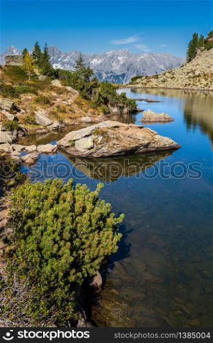 Sunny autumn alpine view. Peaceful mountain forest lake with clear transparent water and reflections. Spiegelsee or Mirror Lake, Reiteralm, Steiermark, Austria.