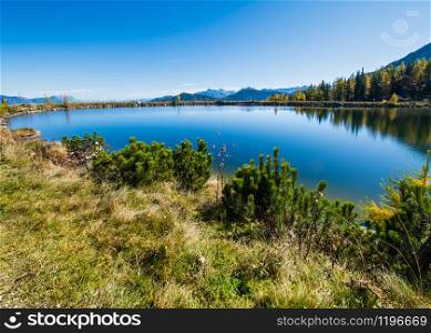 Sunny autumn alpine view. Peaceful mountain lake with clear transparent water and reflections. Reiteralm, Steiermark, Austria.