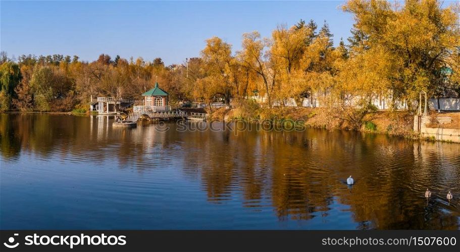 Sunny autumn evening on the blue lake with yellow trees. The Ivanki village in Cherkasy region, Ukraine. Sunny autumn evening on the blue lake