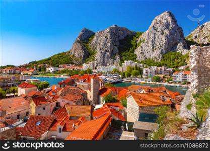 Sunny beautiful aerial view of Cetina river, mountains and red roofs of Old town in Omis, very popular tourist spot in Croatia. Sunny town and port Omis, Croatia