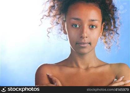 sunny beautiful mulatto woman is looking at camera on sky background