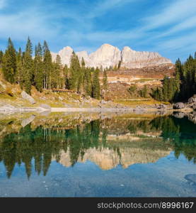 Sunny colorful autumn alpine Dolomites mountain scene, Sudtirol, Italy. Karersee or Lago di Carezza view. Picturesque traveling, seasonal, nature and countryside beauty concept scene.