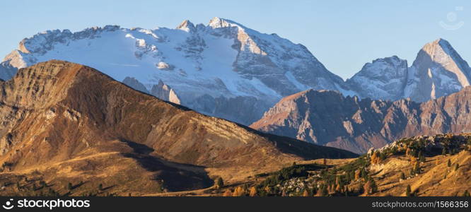 Sunny colorful autumn alpine Dolomites rocky mountain scene, Sudtirol, Italy. Peaceful view from Falzarego Pass. Snowy Marmolada massif and Glacier in far.