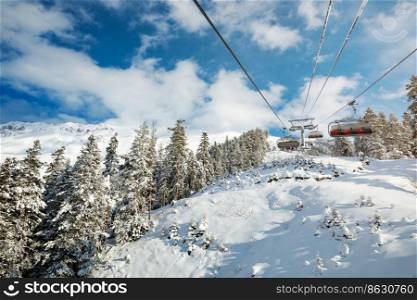 Sunny day at a ski resort. A ropeway over the forest