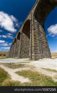 Sunny day close to the sunlit arches of the Ribblehead Viaduct, landscape. North Yorkshire, Europe, England, portrait and wide angle.