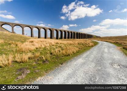 Sunny day with path up to to the sunlit arches of the Ribblehead Viaduct, landscape. North Yorkshire, Europe, England, landscape and wide angle.