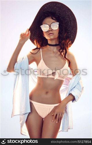 Sunny fashion photo of beautiful slender woman in pink bikini and black hat. Beach summer vibes