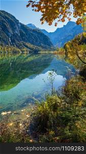 Sunny idyllic colorful autumn alpine view. Peaceful mountain lake with clear transparent water and reflections. Almsee lake, Upper Austria.