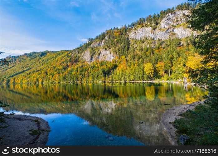 Sunny idyllic colorful autumn alpine view. Peaceful mountain lake with clear transparent water and reflections. Langbathseen lake, Upper Austria. People unrecognizable.
