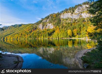 Sunny idyllic colorful autumn alpine view. Peaceful mountain lake with clear transparent water and reflections. Langbathseen lake, Upper Austria. People unrecognizable.
