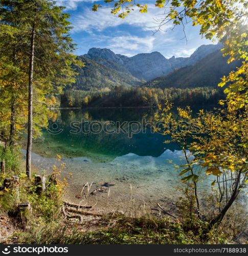Sunny idyllic colorful autumn alpine view. Peaceful mountain lake with clear transparent water and reflections. Langbathseen lake, Upper Austria. There is some sun and lens flares effect.