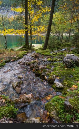 Sunny idyllic colorful autumn alpine view. Peaceful mountain lake with clear transparent water and reflections. Gosauseen or Vorderer Gosausee lake, Upper Austria.