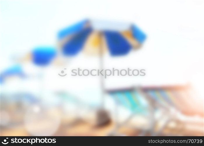 Sunny sandy beach with umbrellas and chairs out of focus - defocused blured background