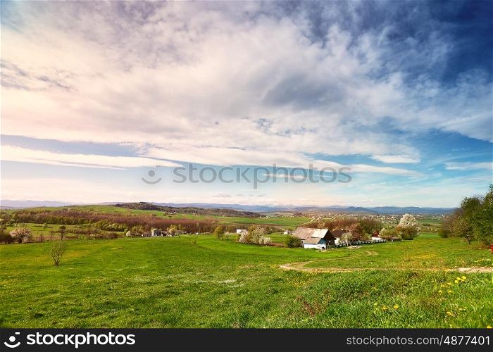 Sunny spring day in village and town on foothills. Mountains on background. Sunny green spring landscape.