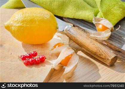Sunny still life with lemon, red currant and cape gooseberry
