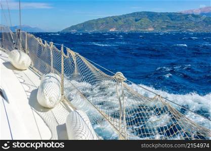 Sunny summer day. Windy weather near the shore of the Gulf of Corinth. Deck of a white sailing yacht with fenders. Sailing Yacht Near the Coast in Windy Weather