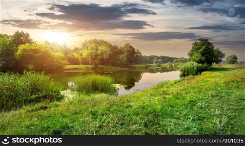 Sunny sunset over calm river in the forest