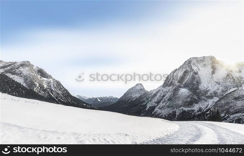 Sunny winter scenery with snow-capped Alps mountain peaks, snow-covered nature, and snowy alpine road, near Ehrwald, Austria, in December.