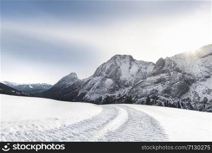 Sunny winter scenery with snow-capped mountains peaks, snow-covered nature, and snowy alpine road, near Ehrwald, Austria. December winter landscape.
