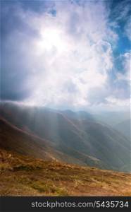 Sunrays through the clouds on the sky in mountains range