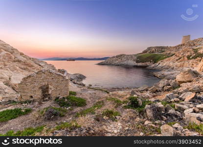 Sunrise as a ferry passes through the bay at Ile Rousse in Corsica with an abandoned building in the foreground and a Genoese tower and mountains of desert des agriates in the background