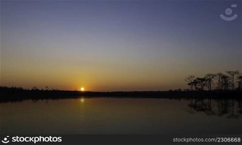sunrise at coast of the lake. Blue sky and sun reflection on water. Nature landscape in asian.