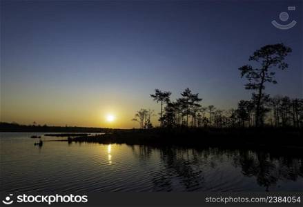 sunrise at coast of the lake. Blue sky and sun reflection on water. Nature landscape in morning