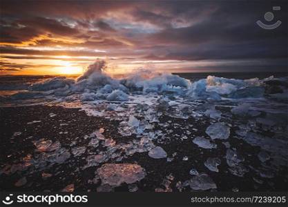 Sunrise at Diamond beach with ices from Jokulsarlon glacier lagoon get washed ashore and strand on the black beach, Iceland