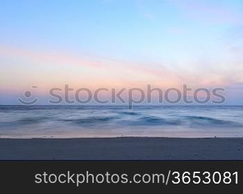 sunrise at sea on beach, waves is blurred with long exposure