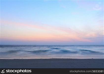 sunrise at sea on beach, waves is blurred with long exposure