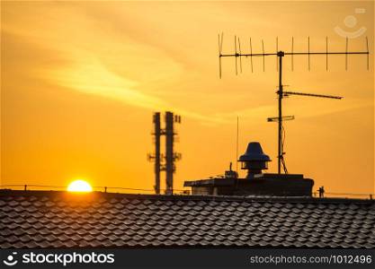 sunrise in in a city with house roof and antenna